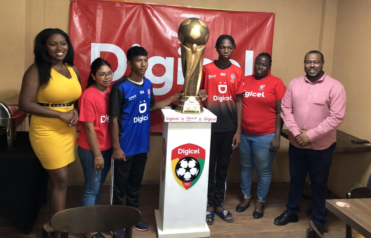Members of the Carmel Secondary and St Ignatius posing with the championship trophy in the presence of Digicel and Petra Organization staffers at the championship pre-match press conference