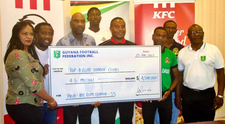 Team Manager of the GDF Randy King (centre) receives the first place prize for winning the Elite League from KFC Guyana Marketing Manager Pamella Manasseh in the presence of captain Kenard Simon.
