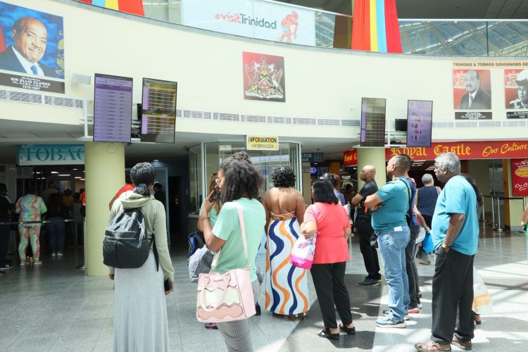 CAL passengers who were stranded over the weekend look at the flight schedules at the Piarco International Airport yesterday.