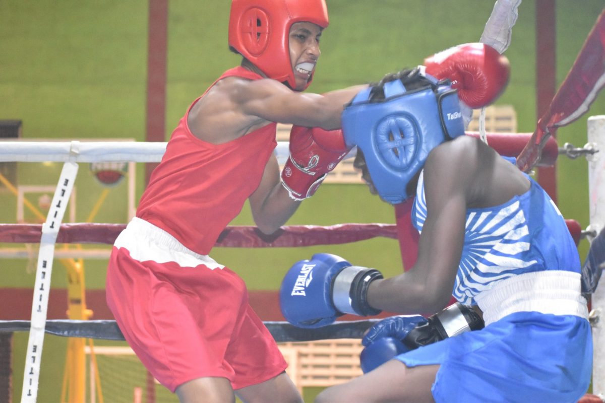 Ryan Rodgers (red) of Guyana lands a glancing jab against Maliki Estwick of Barbados in the Schoolboy Light Bantamweight 52KG final Saturday night at the National Gymnasium.