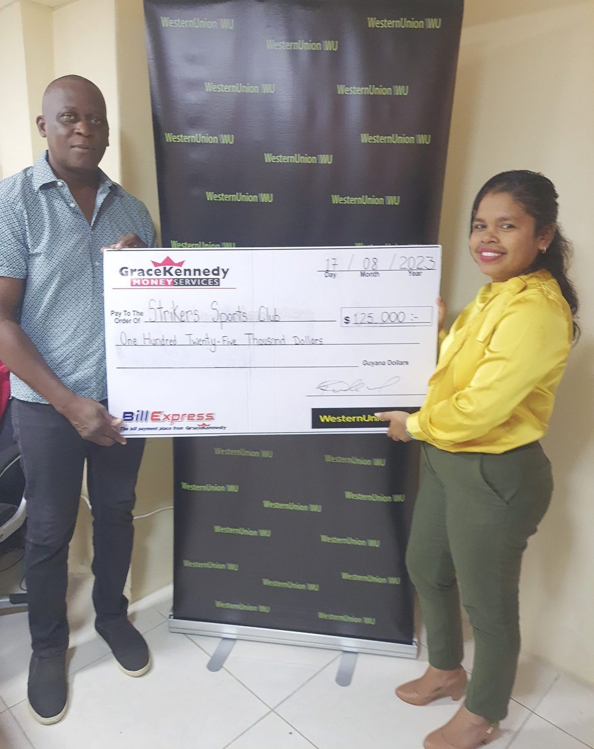 Marketing Assistant Tina Seabra-Gibson hands over the sponsorship check to 
co-organizer Roderick Harry.