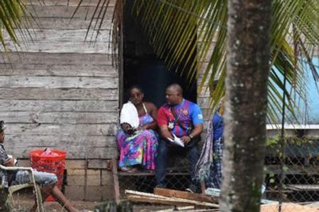 A police officer speaks to Anisa Mohammed, whose three daughters and son were murdered in a mass shooting on Thursday morning at La Retreat Extension, Arima. Five other persons were also shot. 