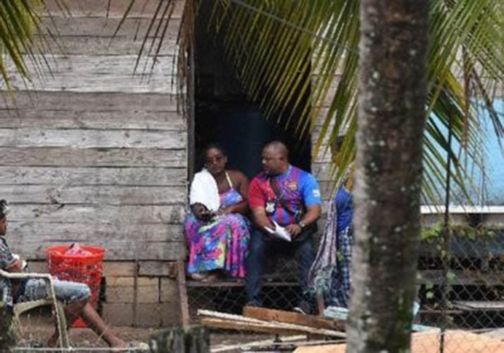 A police officer speaks to Anisa Mohammed, whose three daughters and son were murdered in a mass shooting on Thursday morning at La Retreat Extension, Arima. Five other persons were also shot. 