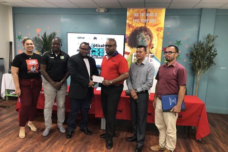 Troy Mendonca (3rd from left), Co-Director of the Petra Organization, receiving the sponsorship cheque Richard Simpson, Courts Optical Chain Manager, in the presence of Christel Van Sluytman (1st from left), Senior Brand Manager of Courts Guyana, GFF Technical Director Brian Joseph (2nd from left), Marti DeSouza (2nd from right), Deputy Chief Education Officer (Hinterland), and Nicholas Fraser, Head of Allied Arts of the Ministry of Education 
