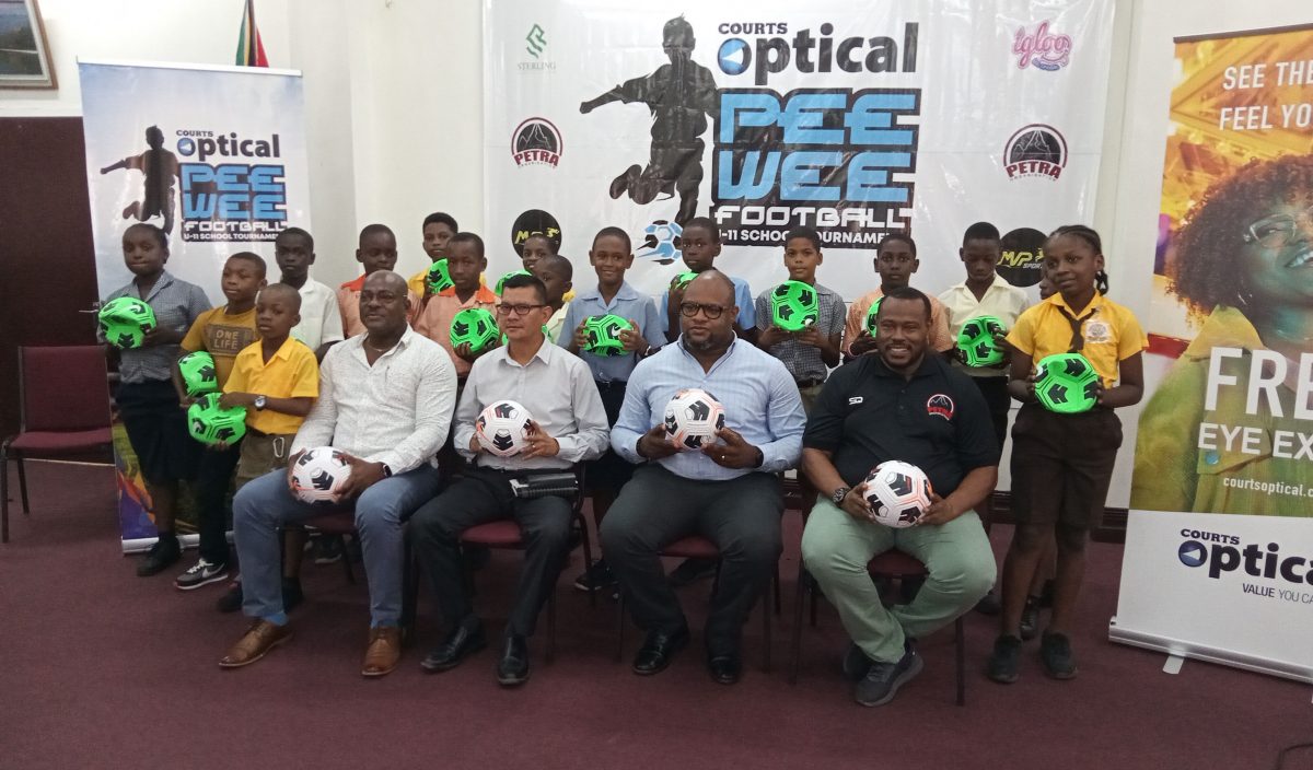 Co-Director of the Petra Organization Troy Mendonca (sitting 1st from right), Richard Simpson, Courts Optical Chain Manager (2nd from right), Marti De Souza, Deputy Chief Education Officer (Hinterland) (3rd from right), and Deputy Director of Sports Franklin Wilson pose with representatives of the competing schools following the end of the ball distribution exercise yesterday