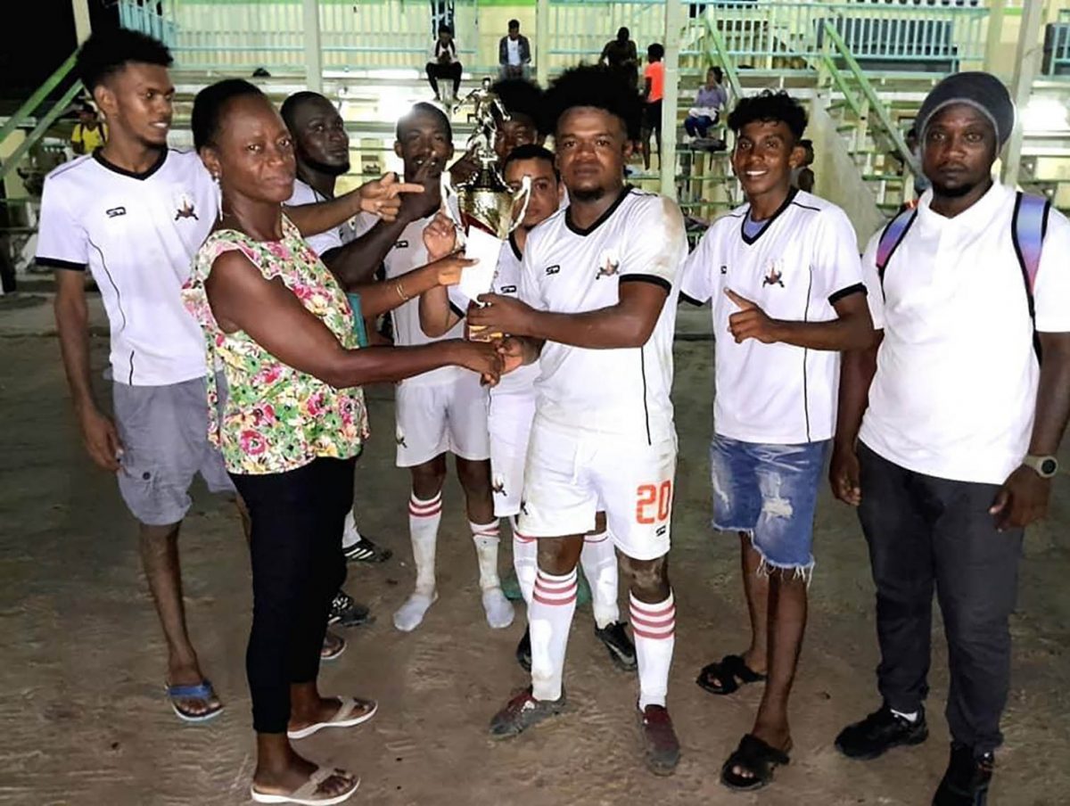 Members of the victorious Beacons outfit receive the championship trophy after winning the Randy Adams Memorial football competition Saturday evening at the Community Centre ground