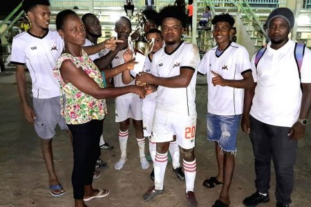 Members of the victorious Beacons outfit receive the championship trophy after winning the Randy Adams Memorial football competition Saturday evening at the Community Centre ground