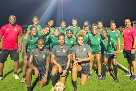 Several members of the Lady Jaguars football team pose alongside head coach Omar Khan (right) and goalkeeper coach Andre Hazel (left)
