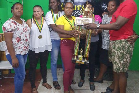 Handing over the winning trophy and cash prizes to the captain Tandica Adams of 1966 LAW surrounded by her jubilant charges is organizer Roderick Harry.
