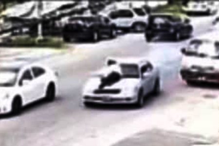 A screenshot from a video of the cop on the bonnet of the vehicle as the driver sped through Main Street 