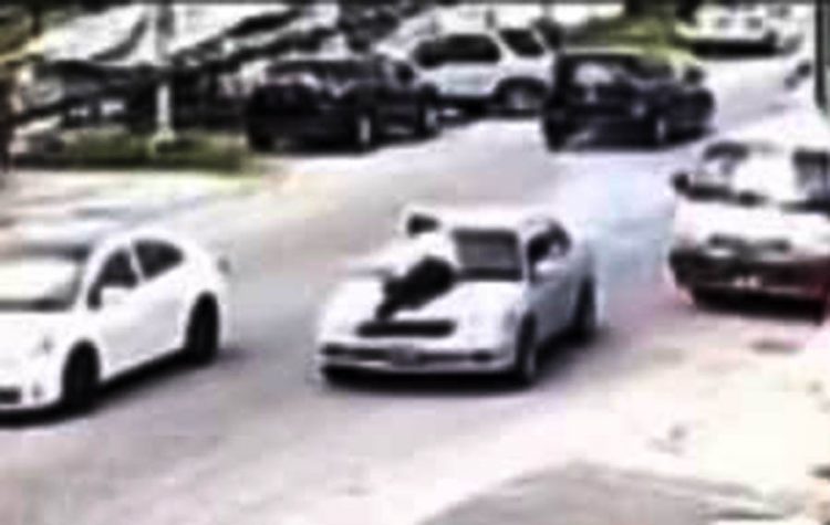 A screenshot from a video of the cop on the bonnet of the vehicle as the driver sped through Main Street 