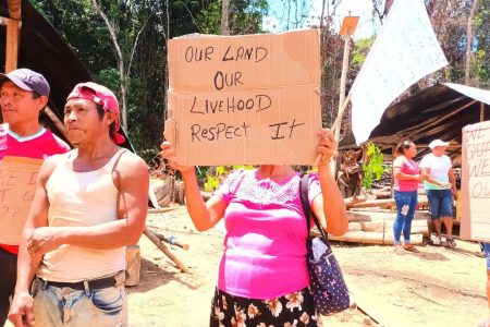 Villagers with placards protesting their forced removal from the mining area
