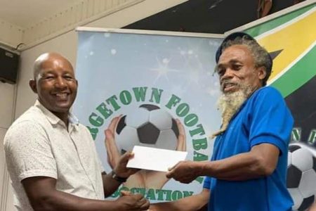 GFA President Otis James (left) presents the championship check to Beacons FC coach Gordon Brathwaite
