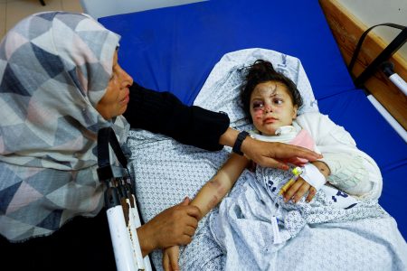 Palestinian girl Fulla Al-Laham, 4, who was wounded in an Israeli strike that killed 14 family members, including her parents and all her siblings, lies on a bed as her grandmother sits next to her, at a hospital in Khan Younis in the southern Gaza Strip, October 14, 2023. REUTERS/Mohammed Salem