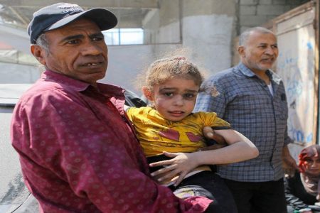 A Palestinian man carries a girl hurt in Israeli strikes in Gaza City October 15, 2023. REUTERS/Mutasem Murtaja Acquire Licensing Rights