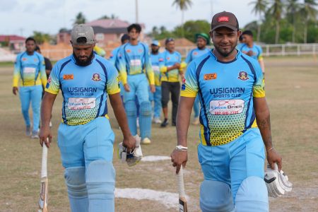 Vishnu Ramjeet (right) and Shazam Ali leading the victorious Lusignan team off the field after their match winning partnership