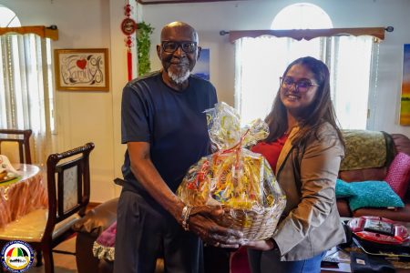 Ancel Lewis being presented with a hamper by the Ministry of Human Services.