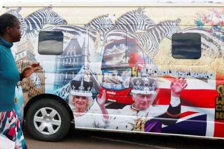 FILE PHOTO: A woman gestures as she walks past a British High Commission (BHC) courtesy van decorated with images of Britain's King Charles and Queen Camilla ahead of their state visit, at the Green Park bus terminus in Nairobi, Kenya October 27, 2023. REUTERS/Thomas Mukoya/File photo