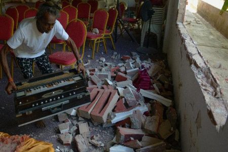 Pooran Nanan, of the Williamsville Hindu Temple, removes a harmonium yesterday from the debris of a ventilation wall which was destroyed. Vandals destroyed two walls of the place of worship to gain entry into the temple, which was vandalised on Saturday afternoon.