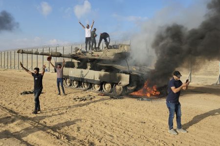 Palestinians celebrate by a destroyed Israeli tank at the Gaza Strip fence east of Khan Younis on Saturday. Photo: AP