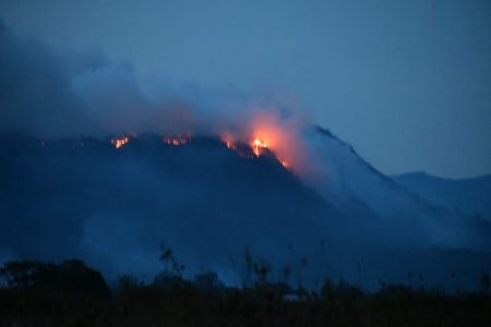 A fire has been raging on a mountain close to the village of Chinoweing in Region Seven as the dry weather takes hold throughout the country. According to Chenapowu resident Michael McGarrell, the fire has been burning for several days.  This photo was taken from a distance of 5km. (Michael McGarrell photo)