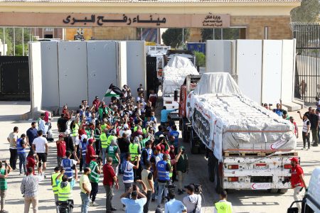 Egyptian volunteers gather and celebrate with a Palestinian flag next to trucks carrying humanitarian aid from Egyptian NGOs driving through the Rafah crossing from the Egyptian side, amid the ongoing conflict between Israel and the Palestinian Islamist group Hamas, in Rafah, Egypt October 21, 2023. REUTERS/Stringer