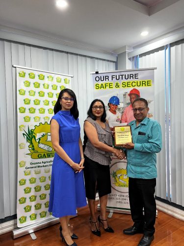 GAWU President Seepaul Narine (right) handing over the award to Serita Chase. At left is Pauline Chase.
