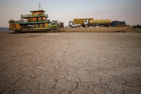 A tug boat and a barge carrying three trucks, 2,000 empty cooking gas cylinders and a backhoe, lie stranded on a sand bank of a diminished Rio Negro river after running aground last month, as the region is hit by a severe drought, in Cacau Pirera, Brazil October 10, 2023. REUTERS/Bruno Kelly 