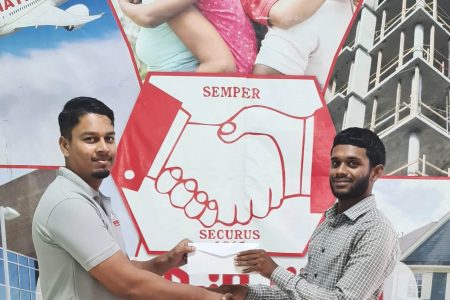 Hand in Hand Mutual Fire Marketing Representative Ryan Shivram (left) hands over the sponsorship check to BMC representative Brandon Persaud.