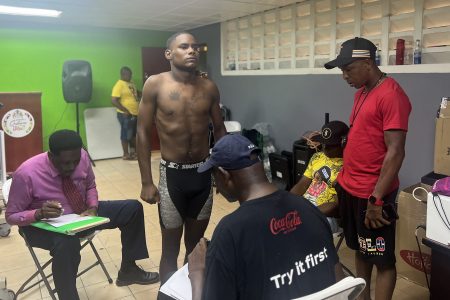 GDF’s Wavel Massiah weighs in as police coach Dexter Marques (right) and FYF coach Sebert Blake (2nd right, sitting) look on