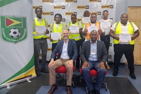 The 11 newly certified excavator operators displaying their credentials alongside MACORP President and General Manager German Consuegra (sitting left), and GFF President Wayne Forde