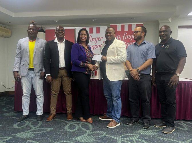 KFC Marketing Manager Pamela Manasseh (centre) hands over the sponsorship package to Petra’s Troy Mendonca while Petra Organisation Referee Consultant Wayne Griffith (1st from left), Assistant Director of Sports Franklin Wilson (2nd from left), Nicholas Fraser (3rd from left), Administrator of the Allied Arts Unit, and GFF Director of Competitions Troy Peters look on.