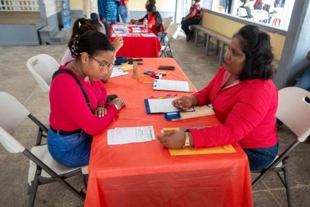 Venita Andrew of CORUM Restaurant Group Inc. (right) shares information with a propective applicant at the Region 3 Chamber of Commerce and Industry Job Fair