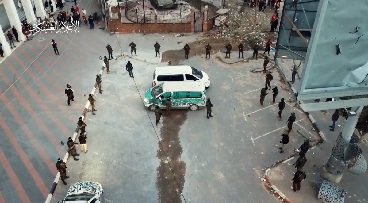 Hamas militants stand by vehicles as they hand over hostages who were abducted during the October 7 attack on Israel to members of the International Committee of the Red Cross, as part of a hostages-prisoners swap deal between Hamas and Israel amid a temporary truce, in an unknown location in the Gaza Strip, in this screengrab taken from video released November 26, 2023. Hamas Military Wing/Handout via REUTERS