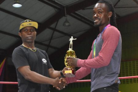 The Forgotten Youth Foundation coach Sebert Blake (left) presents the ‘Best Boxer’ accolade to his fighter Septon Barton at the recently concluded Lennox Blackmoore National Intermediate Championship.
