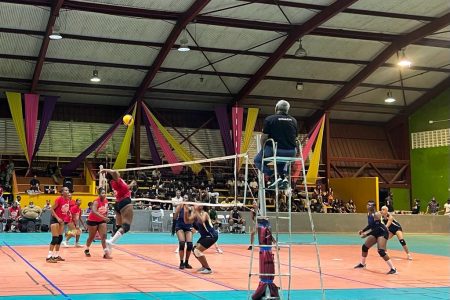 A Mont Joly (French Guiana) player (in red) goes for a spike during their match against the Demerara female team
