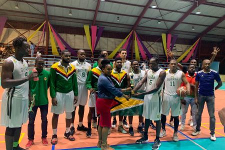 Dianna Khan, wife of late basketball stalwart and GDF Warrant Officer Jason Khan, presents the trophy, which was named after her husband, to Guyana’s captain Harold Adams in the presence of teammates and coaches following their victory over Suriname