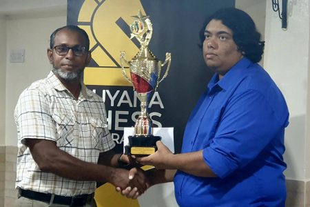 CM Taffin Khan receiving the Senior National Championship trophy from Vice-president of the Guyana Chess Federation Irshad Mohamed after winning the national playoff against Loris Nathoo