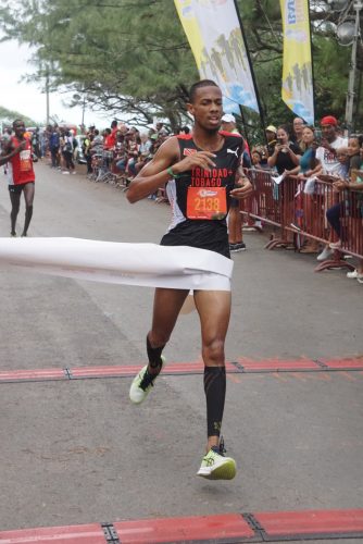 Nicholas Romany of Trinidad crossed the finish line first on the tree-lined highway in the 10K event. Alex Ekesa, who trails, finished second, while Darren Matthews completed the podium. (Emmerson Campbell photo)