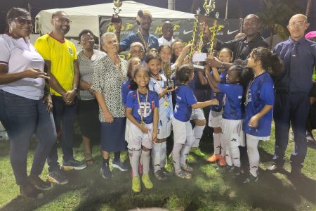 Marian Academy skipper Skylar DeNobrega receives the winner’s trophy from GFF President Wayne Forde as her teammates, coach, and teachers look on