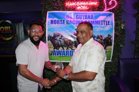 Former Guyana and West Indies cricket Test spinner Devendra Bishoo (left) presents the Horse of the Year accolade to Spankhurst trainer Damain Dharamjit.