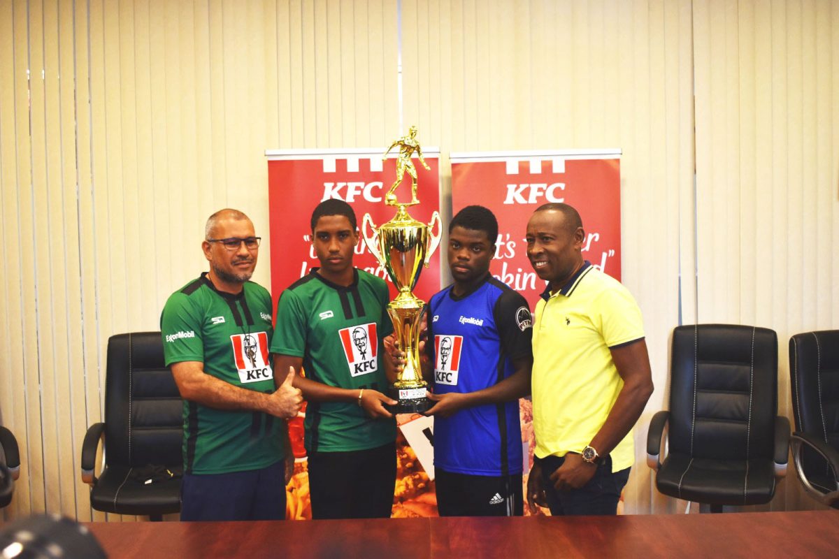 St. Benedict’s College Team Manager Gregory Quan Kep (left), Captain Jeremiah Joseph (2nd from left), Clarendon College skipper Deandre Gallimore (2nd from right), and Team Manager Richard Palmer pose with the KFC International Goodwill Football Championship trophy.