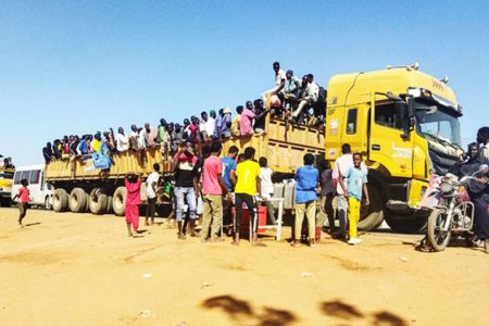 People displaced by the conflict in Sudan get on top of the back of a truck moving along a road in Wad Madani, the capital of al-Jazirah state, on December 16, 2023. (AFP) 