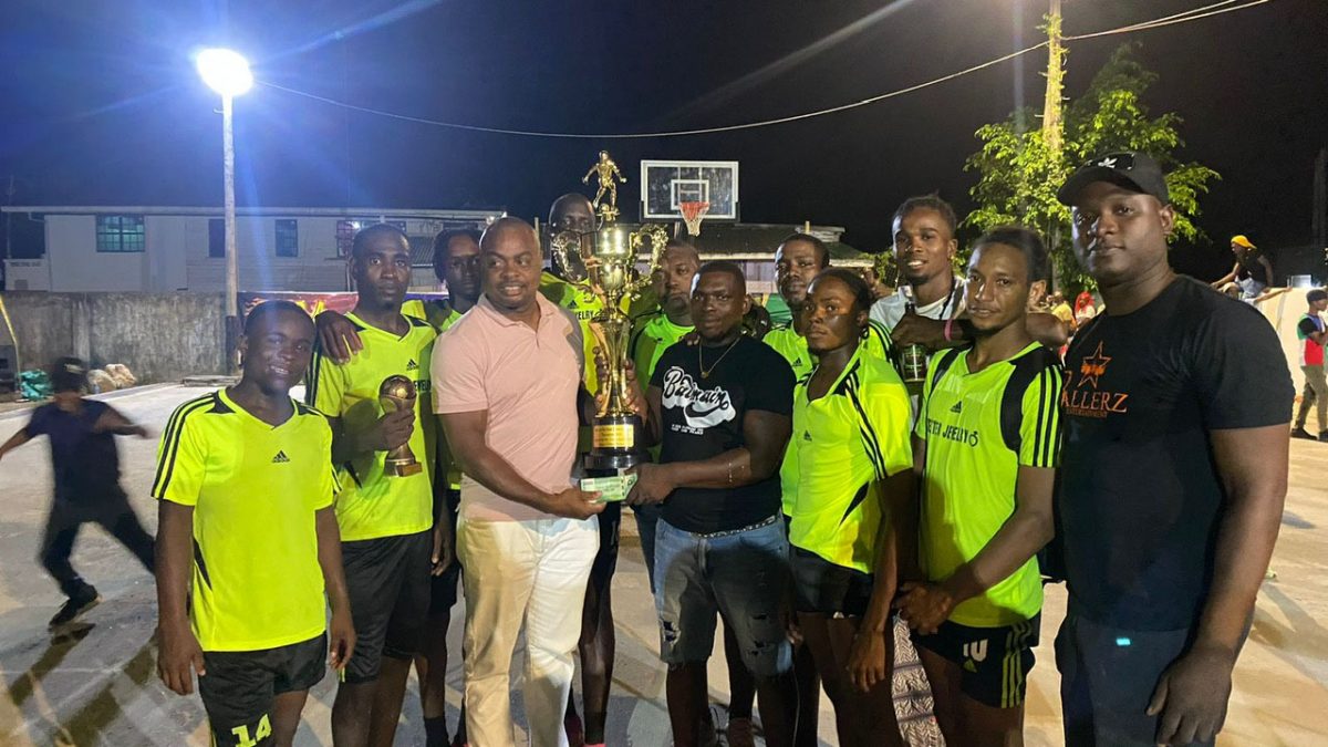 Tournament representative Edison Jefford (3rd from left) presents the championship trophy to the victorious Stabroek Ballers outfit