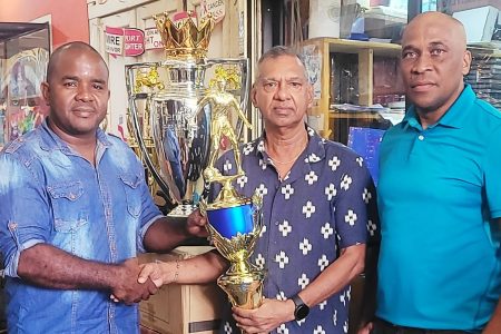 Trophy Stall proprietor Ramesh Sunich (centre) presents the championship trophy to tournament consultant Keeran Williams in the
presence of referees coordinator Stanley Lancaster