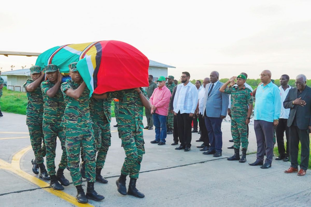 Draped in the flag of Guyana: One of the bodies of the five servicemen who perished in a helicopter crash on Wednesday being borne from an aircraft at the EFCIA, Ogle in the presence of Commander-in-Chief of the Armed Forces, President Irfaan Ali and the Chief of Staff of the Guyana Defence Force, Brigadier Omar Khan and others. (Office of the Prime Minister photo)