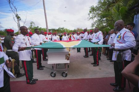 The casket with the remains of Mike Charles being draped with the flag of Guyana yesterday. (Office of the President photo)