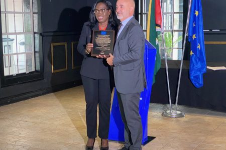 Coordinator of WAD, Clonel Samuels-Boston (left) with the award. At right is Head of Cooperation of the EU Delegation, Joan Nadal-Sastre.
