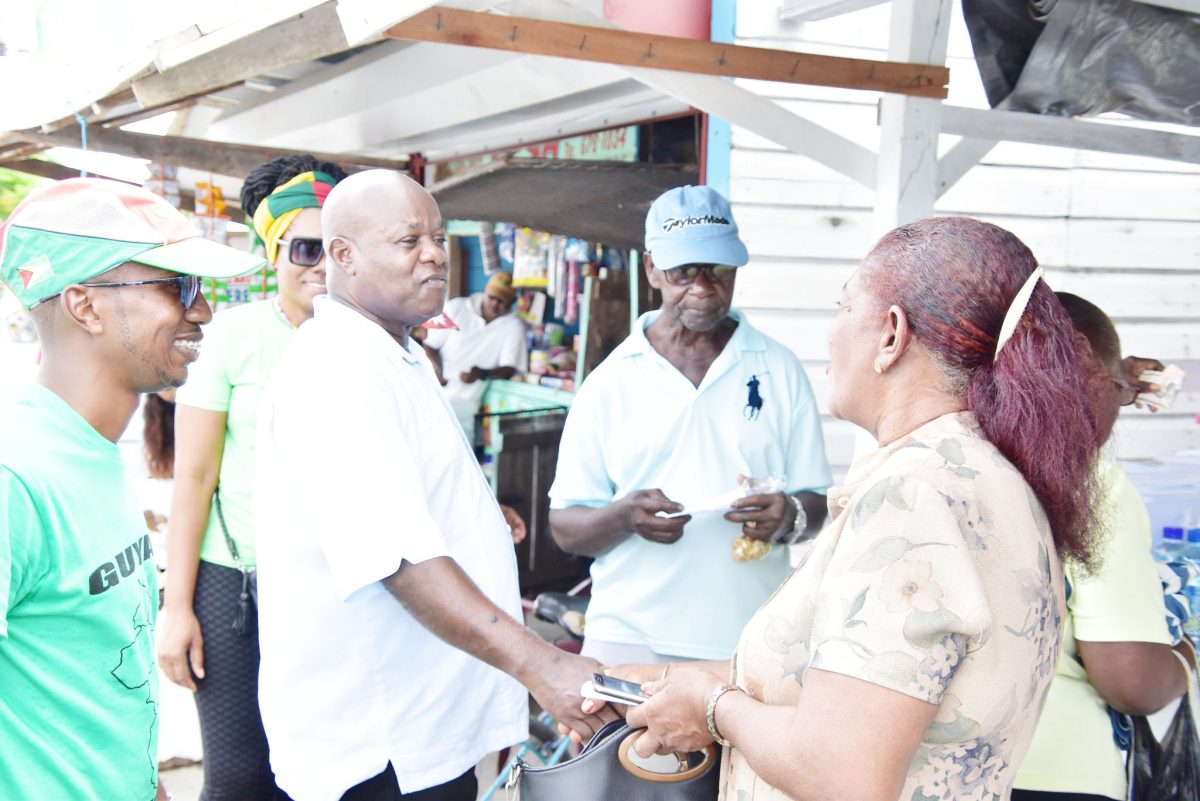 Aubrey Norton (second from left) greeting a resident of Essequibo
