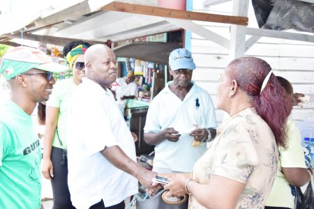 Aubrey Norton (second from left) greeting a resident of Essequibo